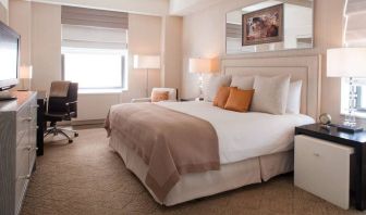 The Benjamin Royal Sonesta New York double bed guest room, including TV, chair, armchair, and window.