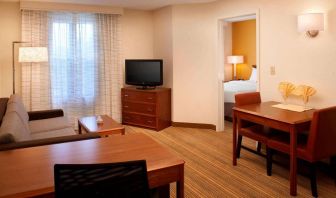 Sonesta ES Suites Chicago Waukegan Gurnee double bed guest room lounge area, featuring sofa, coffee table, and TV.