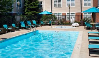 The outdoor pool at Sonesta ES Suites Chicago Waukegan Gurnee ha a nearby hot tub, shaded tables and chairs, and sun loungers and chairs by the side of the pool.