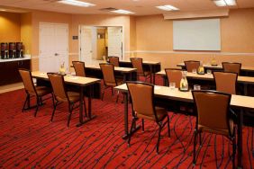 Hotel meeting room, with seating for a dozen attendees, and tables arranged in a classroom format facing a whiteboard.