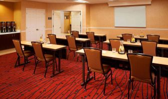 Hotel meeting room, with seating for a dozen attendees, and tables arranged in a classroom format facing a whiteboard.