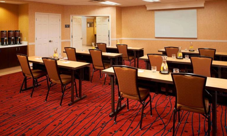 Hotel meeting room, with seating for a dozen attendees, and tables arranged in a classroom format facing a whiteboard.