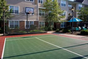 Sonesta ES Suites Chicago Waukegan Gurnee’s basketball court is next to the pool and has a fence beside the hoop.