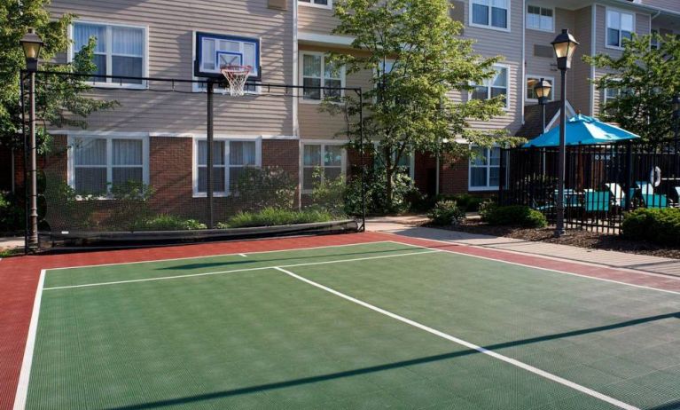 Sonesta ES Suites Chicago Waukegan Gurnee’s basketball court is next to the pool and has a fence beside the hoop.