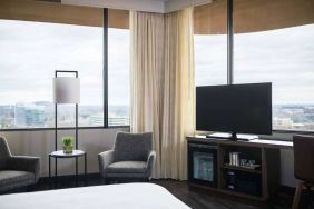 Sonesta Nashville Airport guest room, featuring widescreen television, chairs and a coffee table, and large windows.