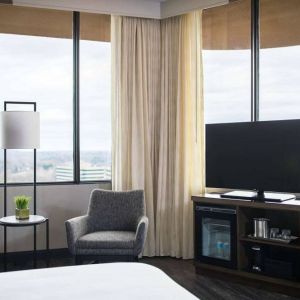 Sonesta Nashville Airport guest room, featuring widescreen television, chairs and a coffee table, and large windows.