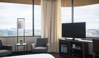 Sonesta Nashville Airport guest room, featuring widescreen television, chairs and a coffee table, and large windows.