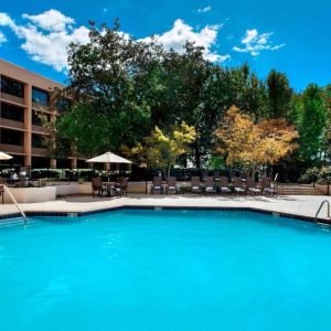 Sonesta Nashville Airport’s outdoor pool has shaded tables and chairs nearby, alongside a row of sun loungers.