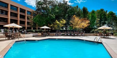 Sonesta Nashville Airport’s outdoor pool has shaded tables and chairs nearby, alongside a row of sun loungers.