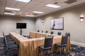 Meeting room in Sonesta Nashville Airport with tables arranged in a U-shape facing  large TV, plus a large artistic photograph of a horse on the wall.