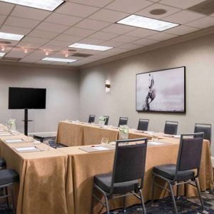 Meeting room in Sonesta Nashville Airport with tables arranged in a U-shape facing  large TV, plus a large artistic photograph of a horse on the wall.