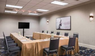 Meeting room in Sonesta Nashville Airport with tables arranged in a U-shape facing  large TV, plus a large artistic photograph of a horse on the wall.