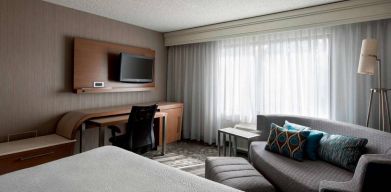 Sonesta Select Tempe Downtown double bed guest room, furnished with TV and sofa, plus workspace desk and chair.