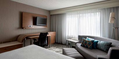 Sonesta Select Tempe Downtown double bed guest room, furnished with TV and sofa, plus workspace desk and chair.