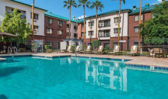 The hotel’s outdoor pool has loungers, as well as a table and chairs, by the side, plus towering trees beyond the fence.