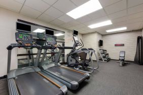 The fitness center in Sonesta Select Tempe Downtown has a wall-mounted TV, free weights, and exercise machines facing a large mirror.