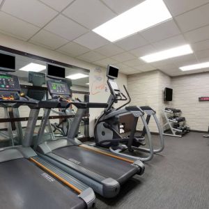 The fitness center in Sonesta Select Tempe Downtown has a wall-mounted TV, free weights, and exercise machines facing a large mirror.