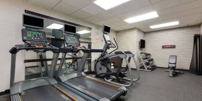 The fitness center in Sonesta Select Tempe Downtown has a wall-mounted TV, free weights, and exercise machines facing a large mirror.