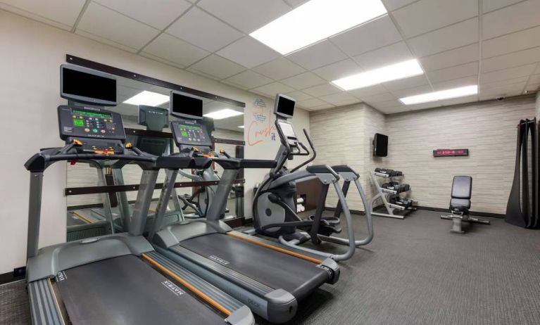 The fitness center in Sonesta Select Tempe Downtown has a wall-mounted TV, free weights, and exercise machines facing a large mirror.