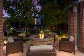 Sonesta Select Tempe Downtown’s fire pit is surrounded by armchairs, with trees nearby and the pool just steps away.