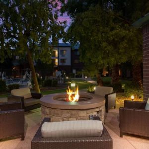 Sonesta Select Tempe Downtown’s fire pit is surrounded by armchairs, with trees nearby and the pool just steps away.