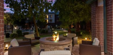 Sonesta Select Tempe Downtown’s fire pit is surrounded by armchairs, with trees nearby and the pool just steps away.