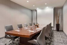 Sonesta Select Tempe Downtown meeting room, featuring long wooden table, a dozen swivel chairs, and a projector screen.