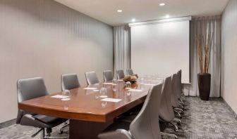 Sonesta Select Tempe Downtown meeting room, featuring long wooden table, a dozen swivel chairs, and a projector screen.