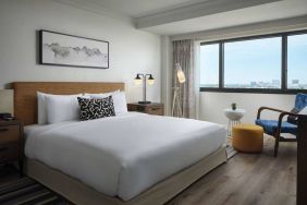 Double bed guest room in Sonesta Irvine, featuring art on the wall, chair, and window.