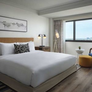 Double bed guest room in Sonesta Irvine, featuring art on the wall, chair, and window.