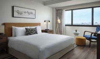 Double bed guest room in Sonesta Irvine, featuring art on the wall, chair, and window.