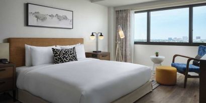 Double bed guest room in Sonesta Irvine, featuring art on the wall, chair, and window.