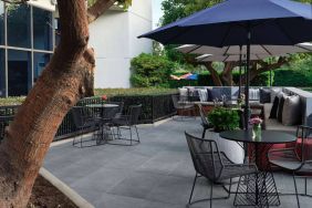 The patio at Sonesta Irvine features sofa seating alongside tables and chairs (shade available), with flowers on each table.