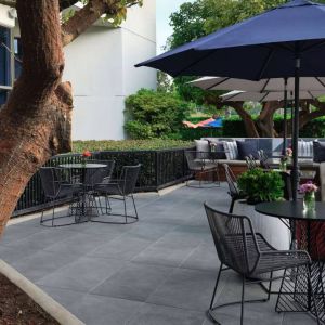 The patio at Sonesta Irvine features sofa seating alongside tables and chairs (shade available), with flowers on each table.