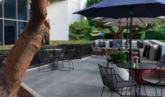 The patio at Sonesta Irvine features sofa seating alongside tables and chairs (shade available), with flowers on each table.