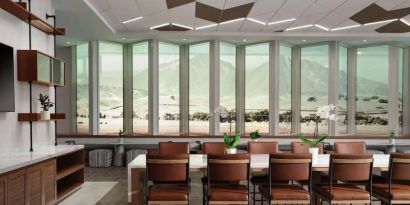 Hotel meeting room, including long table, high ceiling, large windows, and a wall-mounted television.