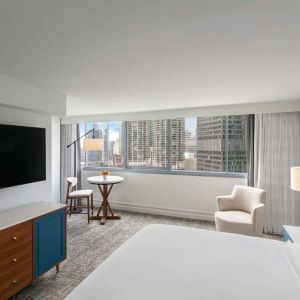 Double bed guest room in Royal Sonesta Chicago Downtown, featuring city views, an armchair, and a large, wall-mounted television.