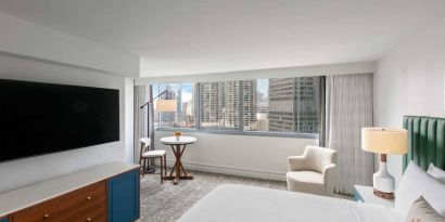 Double bed guest room in Royal Sonesta Chicago Downtown, featuring city views, an armchair, and a large, wall-mounted television.