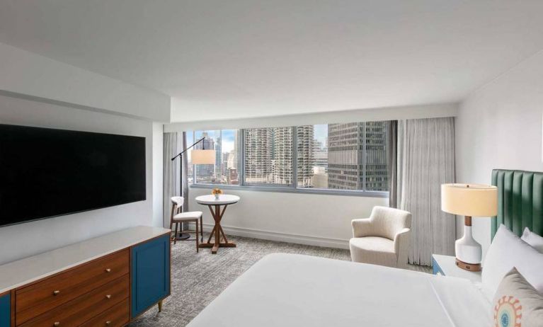 Double bed guest room in Royal Sonesta Chicago Downtown, featuring city views, an armchair, and a large, wall-mounted television.