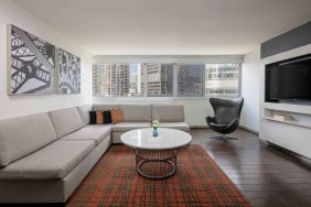 Royal Sonesta Chicago Downtown guest room lounge, with large sofa, chair, and coffee table, plus a wall-mounted TV.