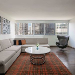 Royal Sonesta Chicago Downtown guest room lounge, with large sofa, chair, and coffee table, plus a wall-mounted TV.