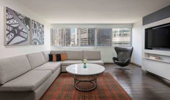 Royal Sonesta Chicago Downtown guest room lounge, with large sofa, chair, and coffee table, plus a wall-mounted TV.