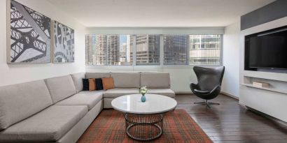 Royal Sonesta Chicago Downtown guest room lounge, with large sofa, chair, and coffee table, plus a wall-mounted TV.