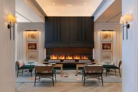 The lobby lounge of Royal Sonesta Chicago Downtown is furnished with comfortable seats and coffee tables close to a fireplace, with art on the walls.