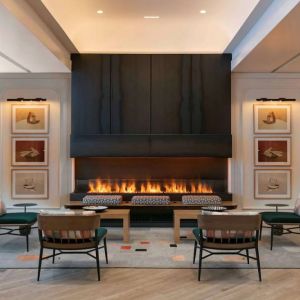 The lobby lounge of Royal Sonesta Chicago Downtown is furnished with comfortable seats and coffee tables close to a fireplace, with art on the walls.