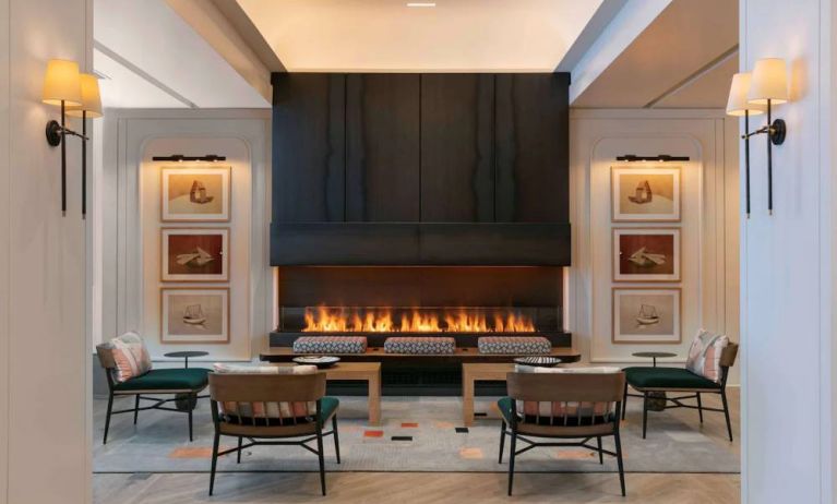 The lobby lounge of Royal Sonesta Chicago Downtown is furnished with comfortable seats and coffee tables close to a fireplace, with art on the walls.