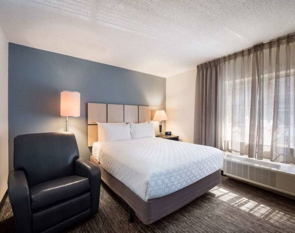 Double bed guest room in Sonesta Simply Suites Phoenix Tempe, featuring an armchair and a window.