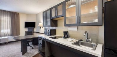 Sonesta Simply Suites Phoenix Tempe guest room kitchen, with hob, microwave, oven, and fridge-freezer, and a nearby TV.