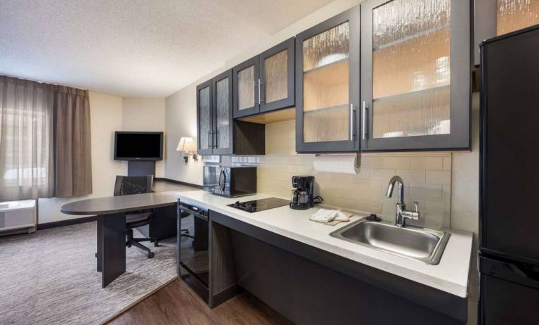 Sonesta Simply Suites Phoenix Tempe guest room kitchen, with hob, microwave, oven, and fridge-freezer, and a nearby TV.