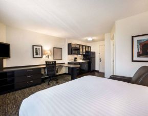 Sonesta Simply Suites Phoenix Tempe double bed guest room, furnished with TV and armchair, plus a workspace desk and chair.